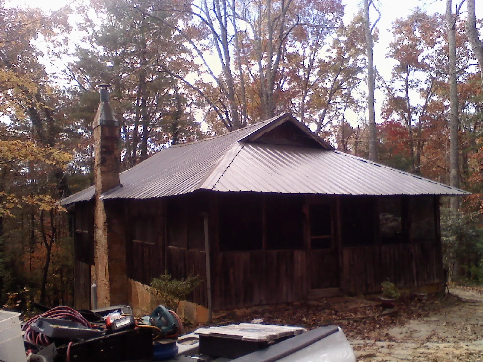 Brown metal hip roof on an old cabin with a stone chimney in Bonlee