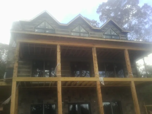 Dormers and porch framing on a large log home under construction — Roof Coating work by our crew in Bonlee