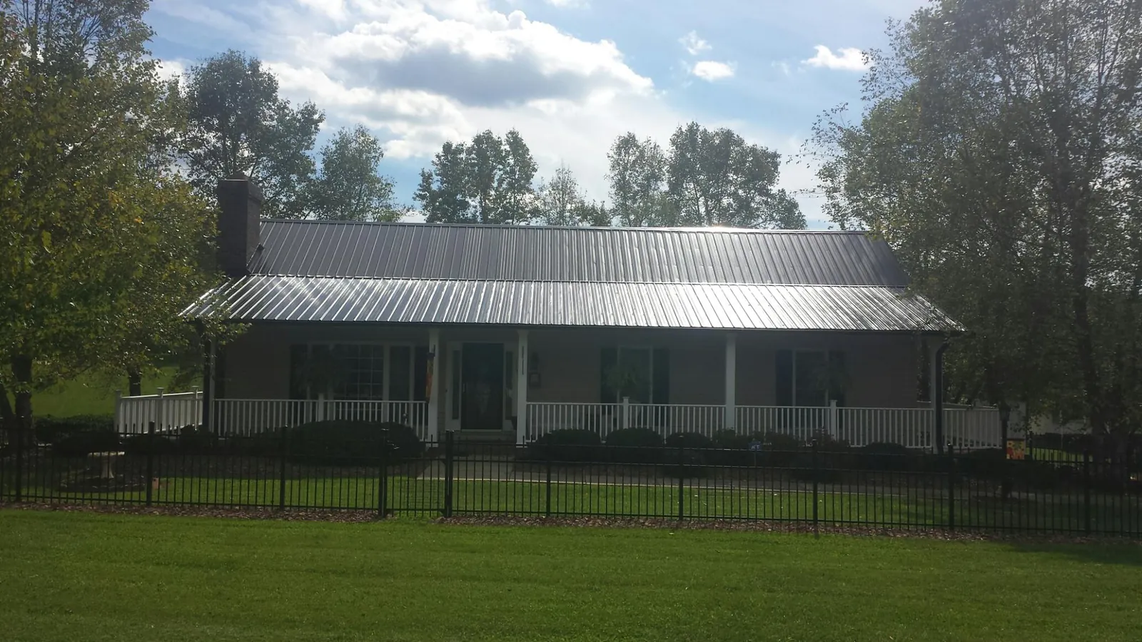 Gray metal roof on a brick ranch with a full width front porch — Gutter Guard Installation work by our crew in Bonlee