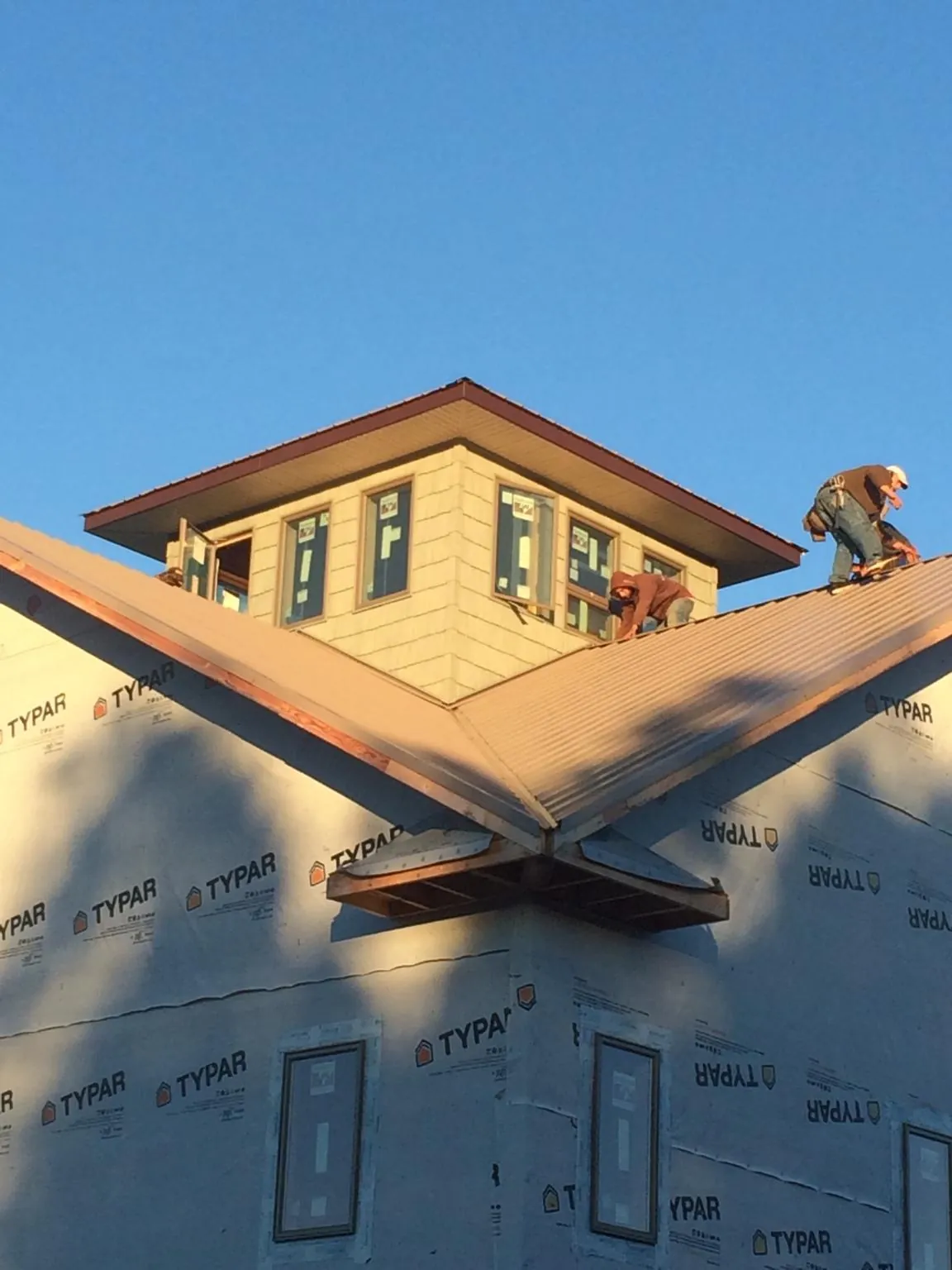 Roofers working around a rooftop cupola on a new metal roof at sunset — Roof Waterproofing in Bonlee by Roofing Brothers